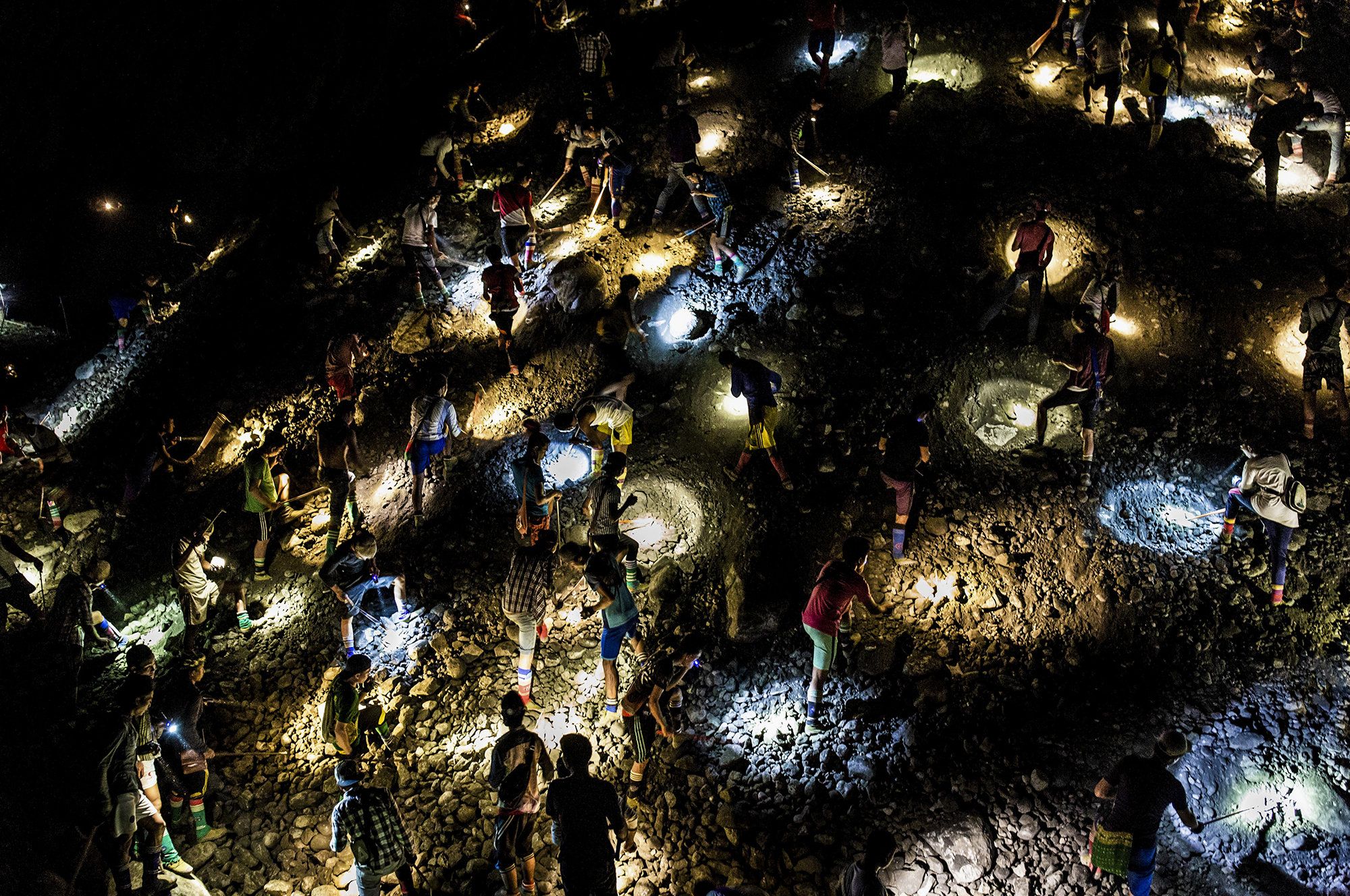 Freelance miners use flashlights to search for jade at night, during company off-hours, in Hpakant in 2019. Image by Hkun Lat. Myanmar, 2019.