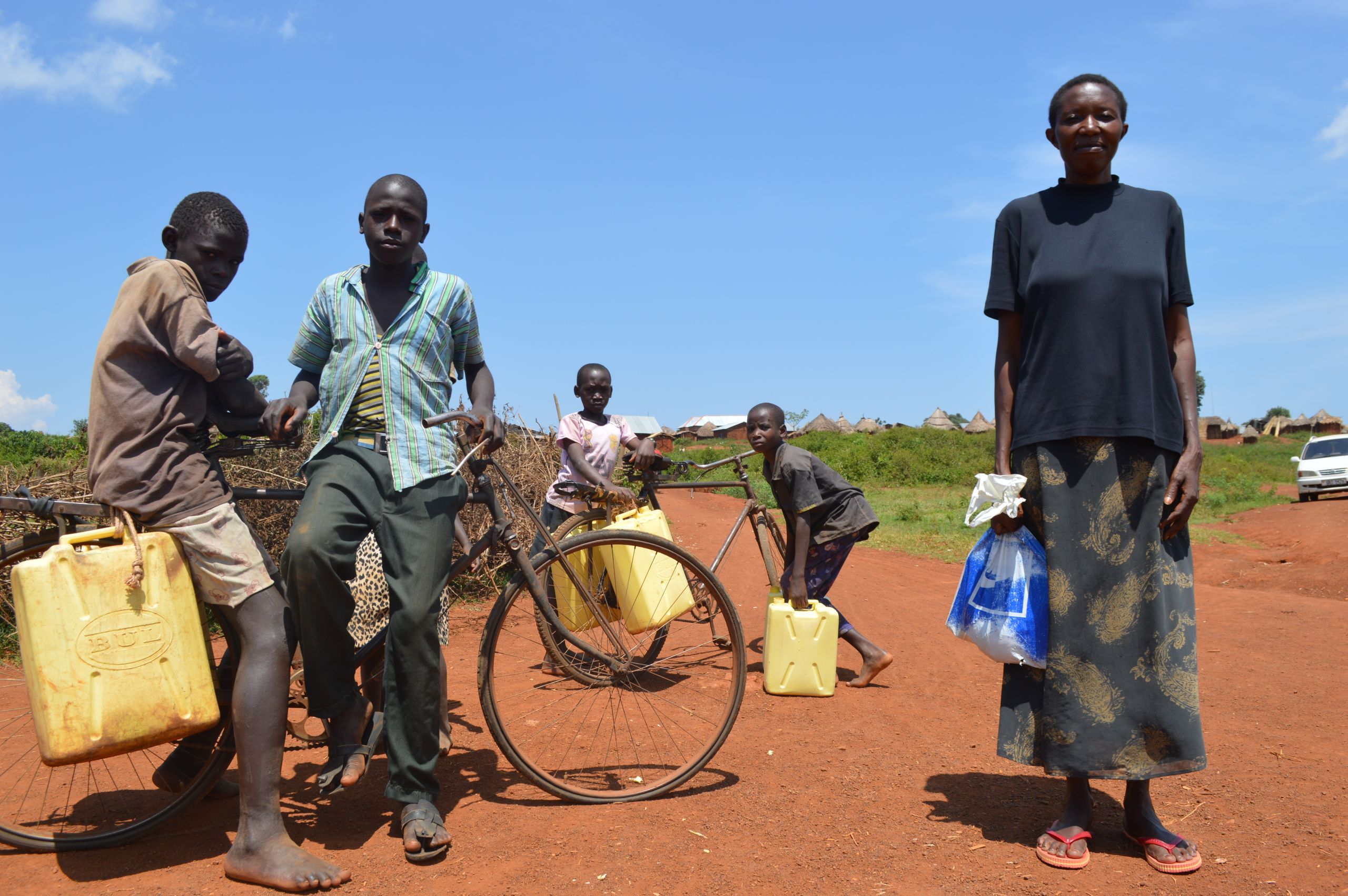 Lilian Omoro, a 20-year resident of Nakalanga village, poses with village children collecting water. Image by Annika McGinnis. Uganda, 2019. 