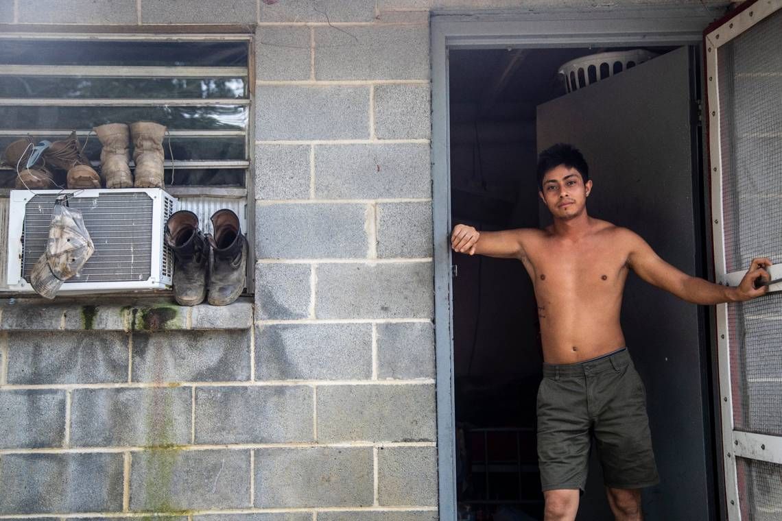 A farmworker named Javier stands in the doorway of his living quarters at a Johnston County farmworker camp on Thursday, August 27, 2020. Air conditioning is considered a luxury by many farmworkers in North Carolina farmworker camps. Image by Travis Long. United States, 2020.