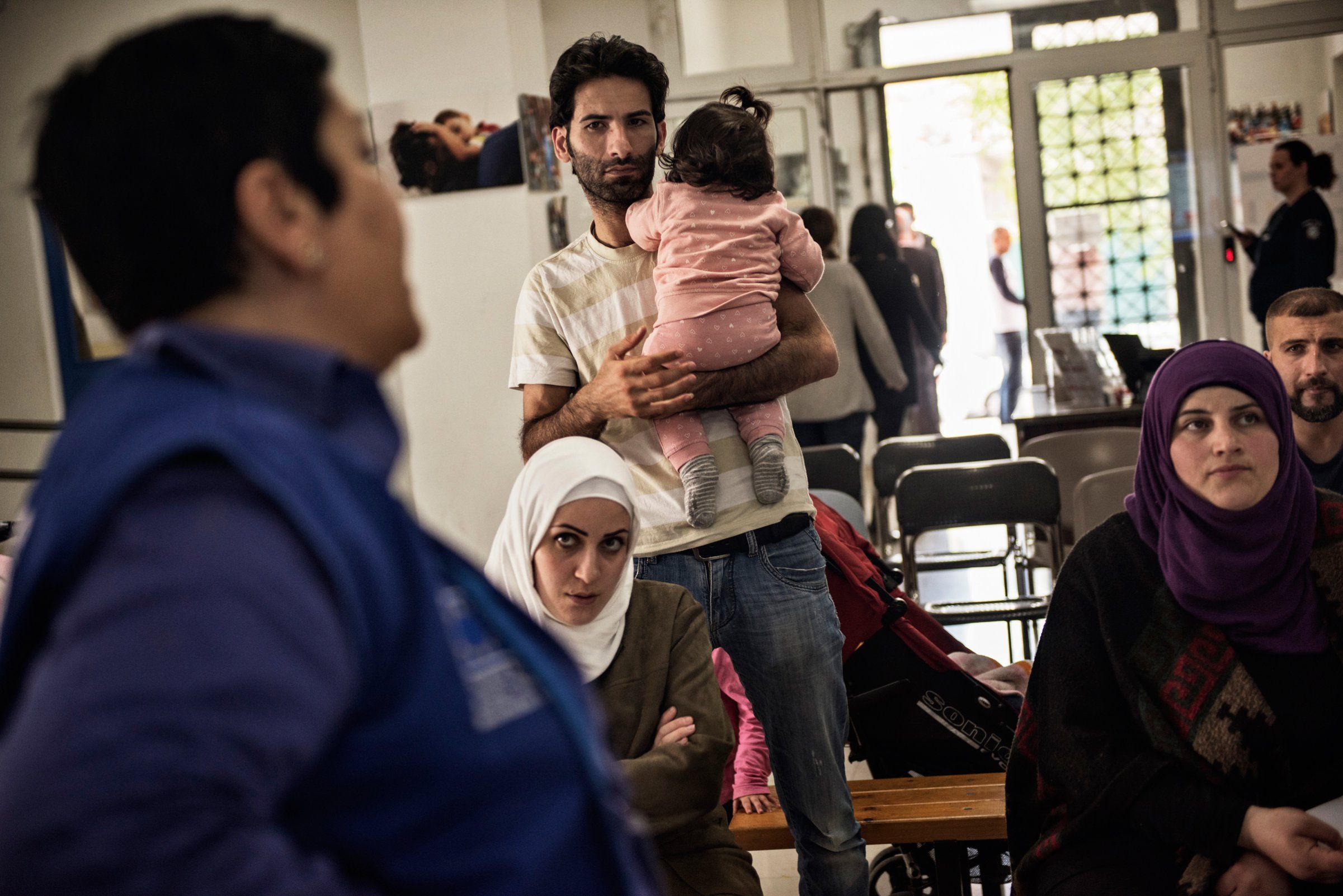 Syrian refugees Taimaa Abzali and her husband Muhanned Abzali, and their six month old daughter, Heln, and son Wael, attend a final orientation meeting at the International Organization for Migration the day before leaving for relocation in Estonia. Image by Lynsey Addario. Greece, 2017.