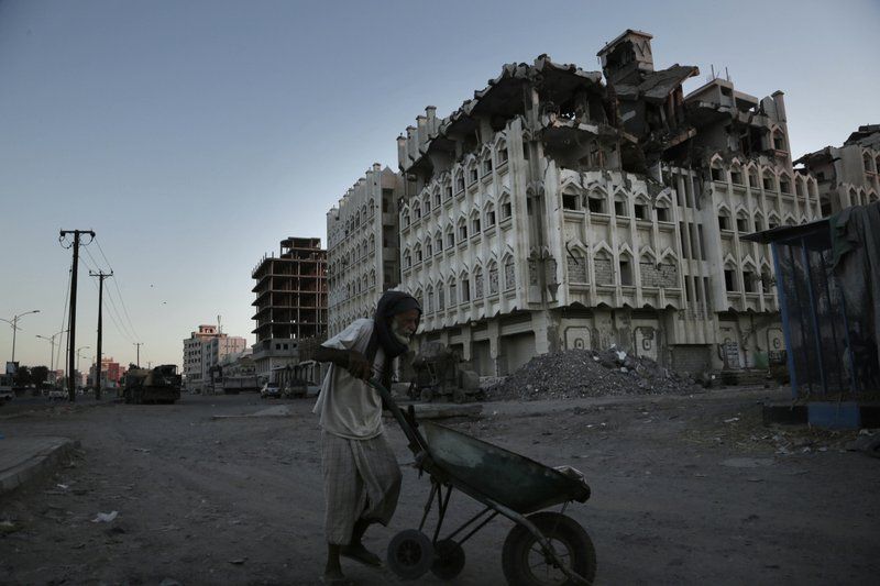 In this Feb. 13, 2018, photo, a elderly man walks past a damaged building from the 2015 war in Aden, Yemen. Violence, famine and disease have ravished the country of some 28 million, which was already the Arab world’s poorest before the conflict began. Image by Nariman El-Mofty. Yemen, 2018. 

