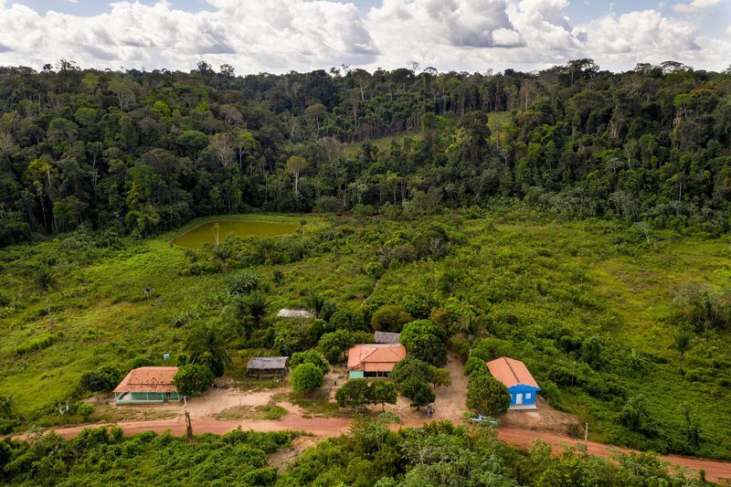 The home of Elias da Silva Lima and his family, center, and a school, left, are pictured in the Virola Jatoba settlement in Anapu. Image by Spenser Heaps. Brazil, 2019.