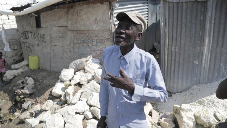 Telfort Innocent, 67, stands in front of his tin shack inside the Teren Toto camp in Delmas, Haiti. Image by Jose A. Iglesias. Haiti, 2019.