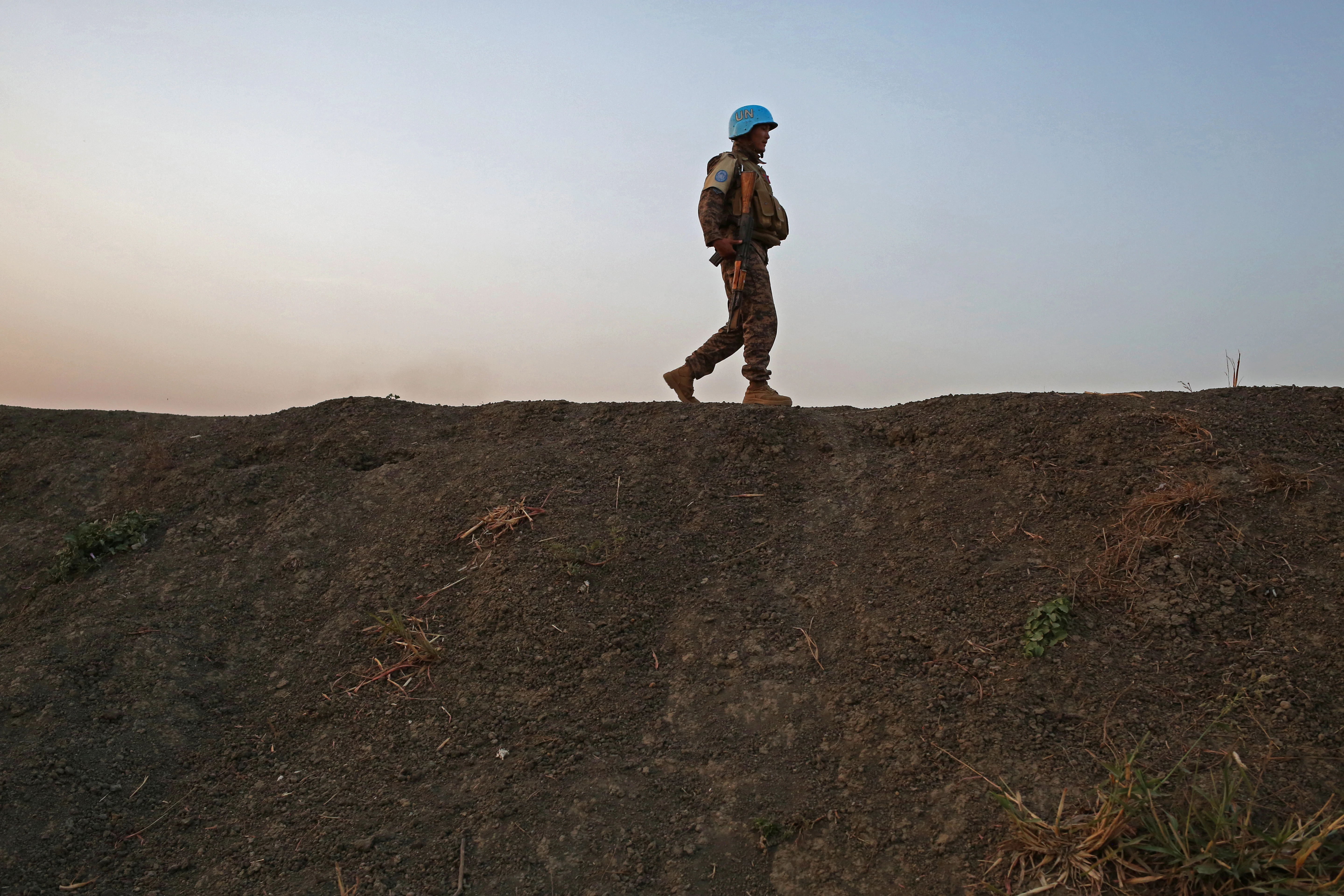 A U.N. peacekeeper patrols the edge of the protection site in Bentiu, South Sudan. Image by Cassandra Vinograd. South Sudan, 2017.

