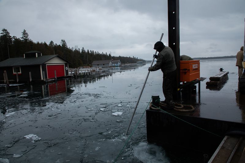 Shane Sutter breaks ice from a barge on Snows Channel at Les Cheneaux Islands in the Upper Peninsula of Michigan on Nov. 20, 2019. He works for Chad Cortes, owner of North Shore Docks in Cedarville. Image by Zbigniew Bzdak / Chicago Tribune. United States, 2020.