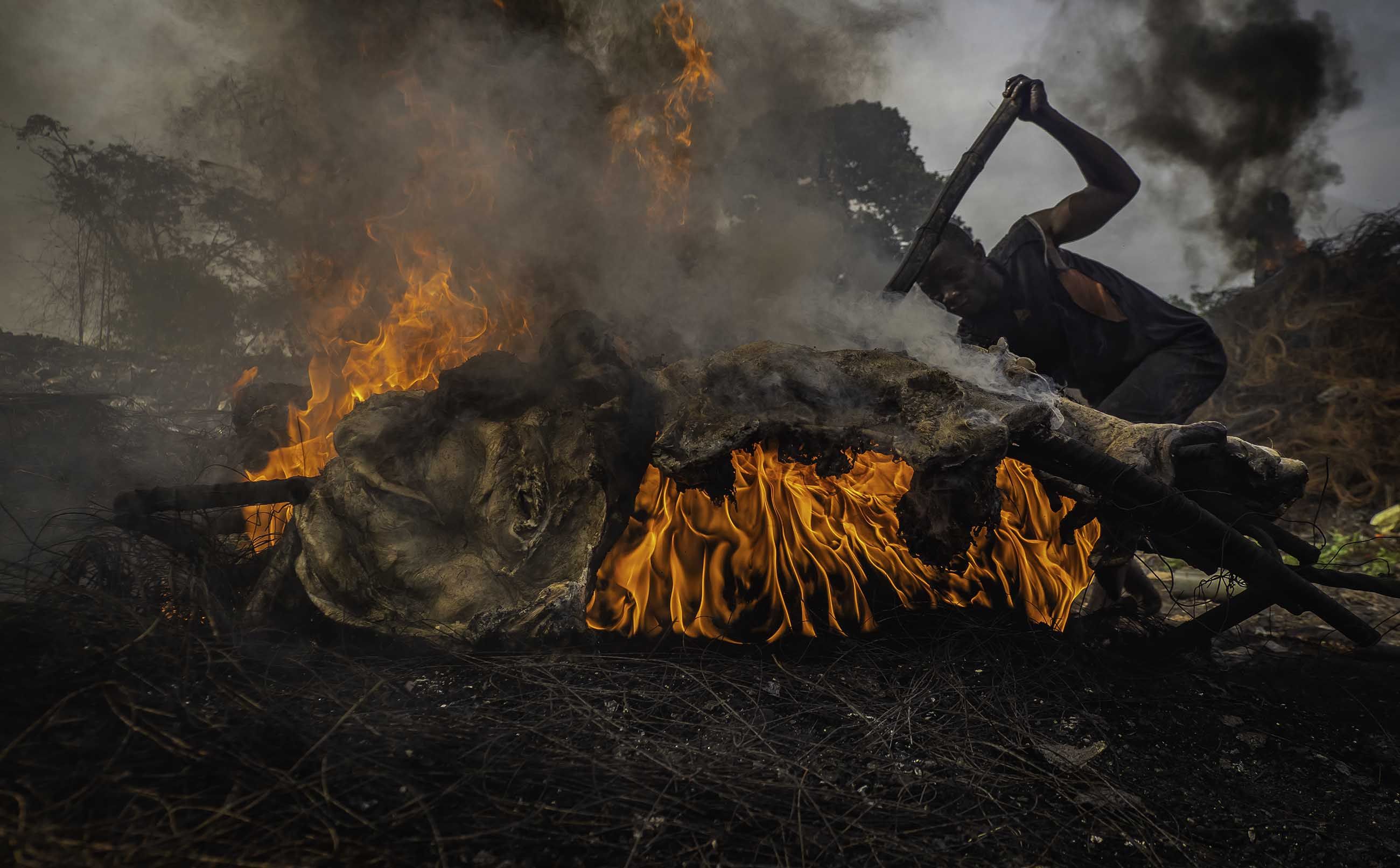 Atop mounds of copper wire, animal bones, and discarded tires, fires burn day and night in Onitsha. Image by Larry C. Price. Nigeria, 2018.