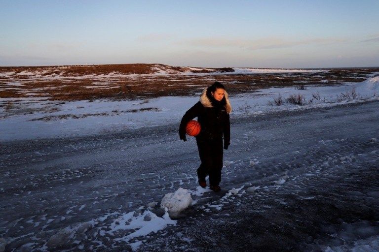 Deidre Levi carries her basketball as she walks to work in St. Michael, Alaska. Levi says she spoke up about being sexually assaulted because she wanted to be a role model for girls in Alaska. Image by Wong Maye-E. United States, 2019.