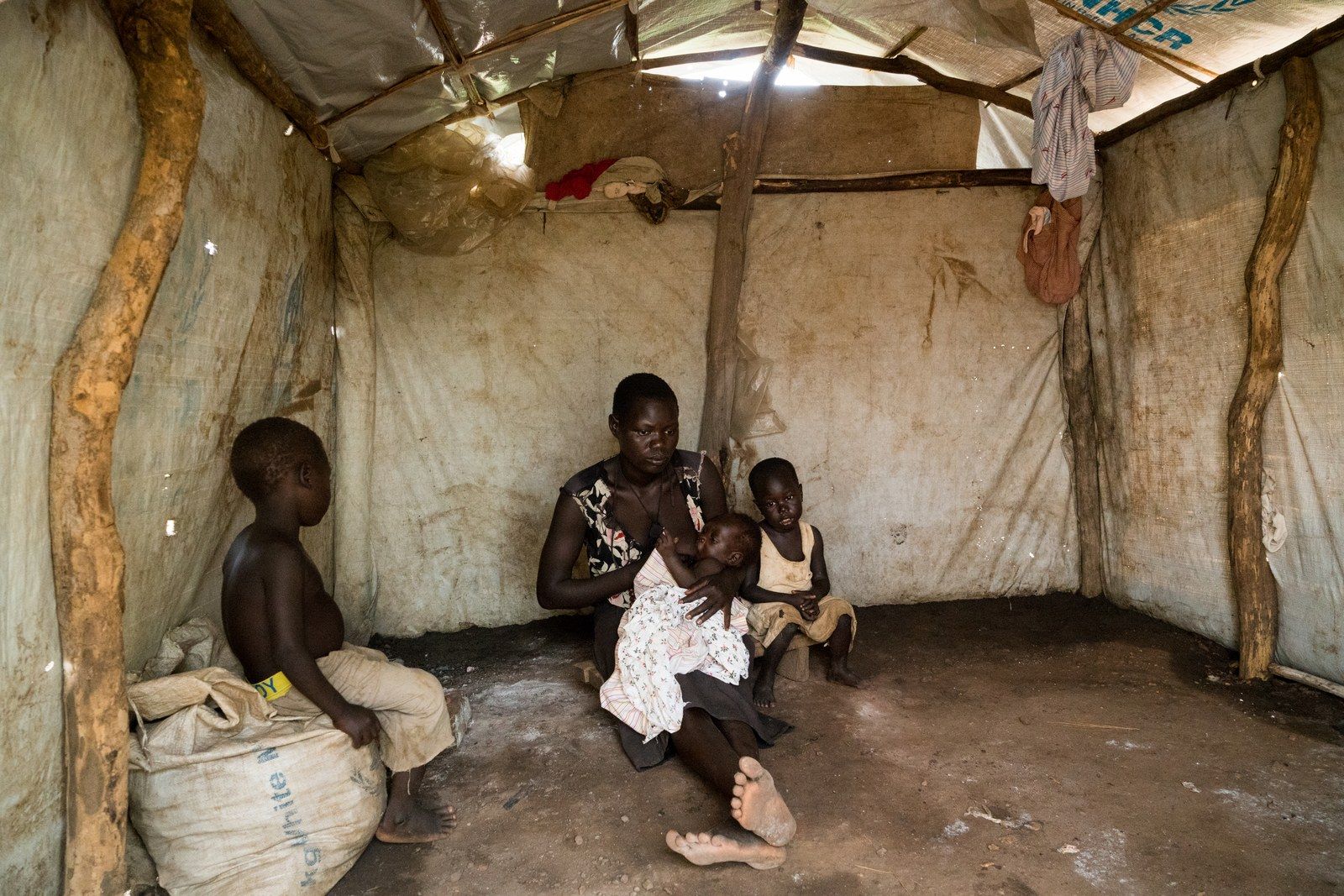 Filda Ayet, age 23, with her three children, Bosco, 5, Winnie, 3, and 3-month-old Peter in their home in a settlement for refugees that have fled from South Sudan to Uganda, June 25, 2019. Image by Adriane Ohanesian. Uganda, 2019.