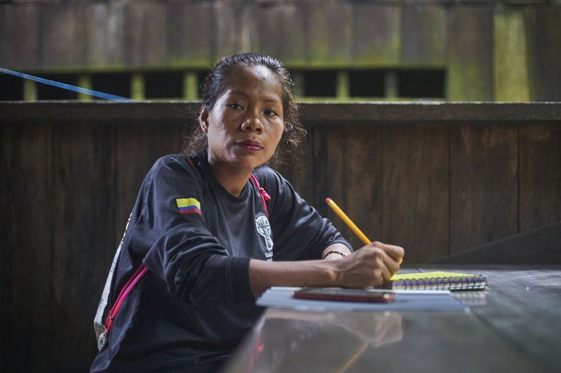 Gloria, one of the women who is part of the San Martín de Amacayacu Indigenous Environmental Guard, sits at a table and takes handwritten notes in pencil during the talk prior to a routine inspection of the Ticuna territory.