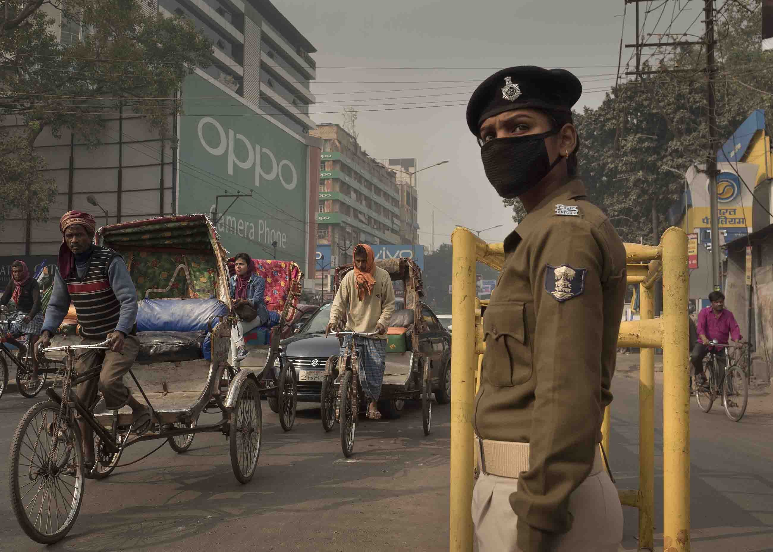 Traffic policewoman Sandhya Bhartj directs traffic in central Patna. Her cloth mask does little to protect her from the smallest particulate pollution. Image by Larry C. Price. India, 2018.