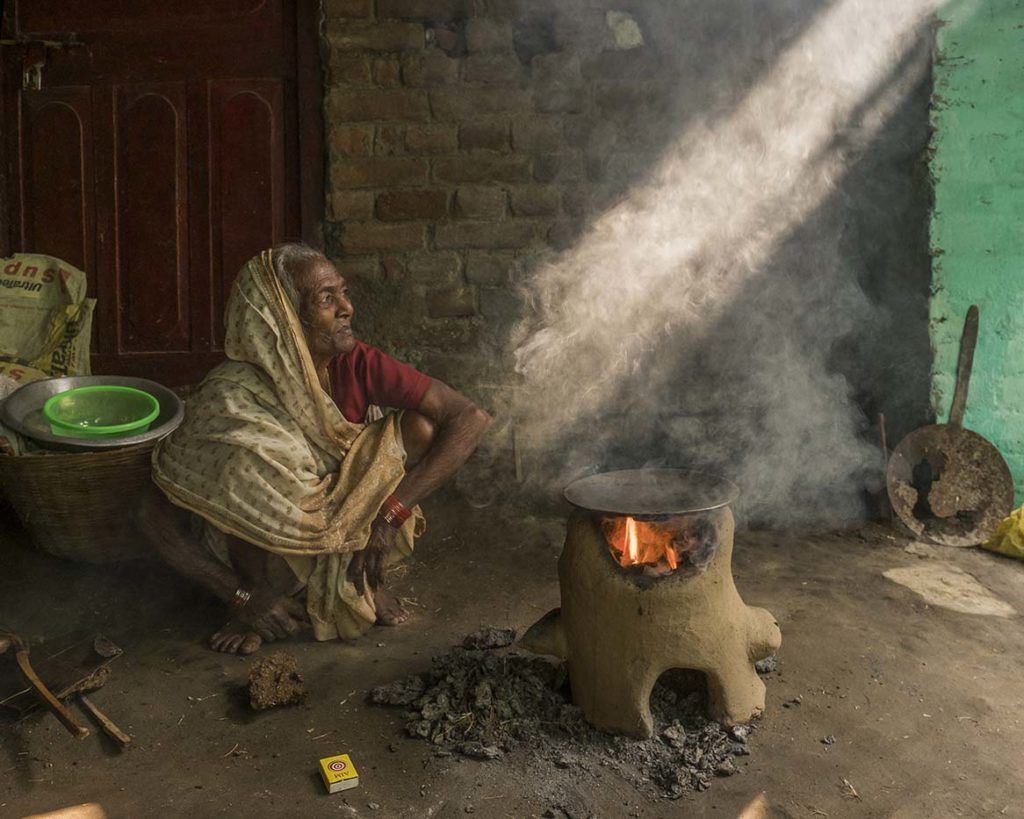 Like many Patna residents, 70-year-old Razia Devi doesn’t connect the coal and dung fires she uses to cook meals and boil water with illnesses — including her husband’s. Image by Larry C. Price. India, 2018.