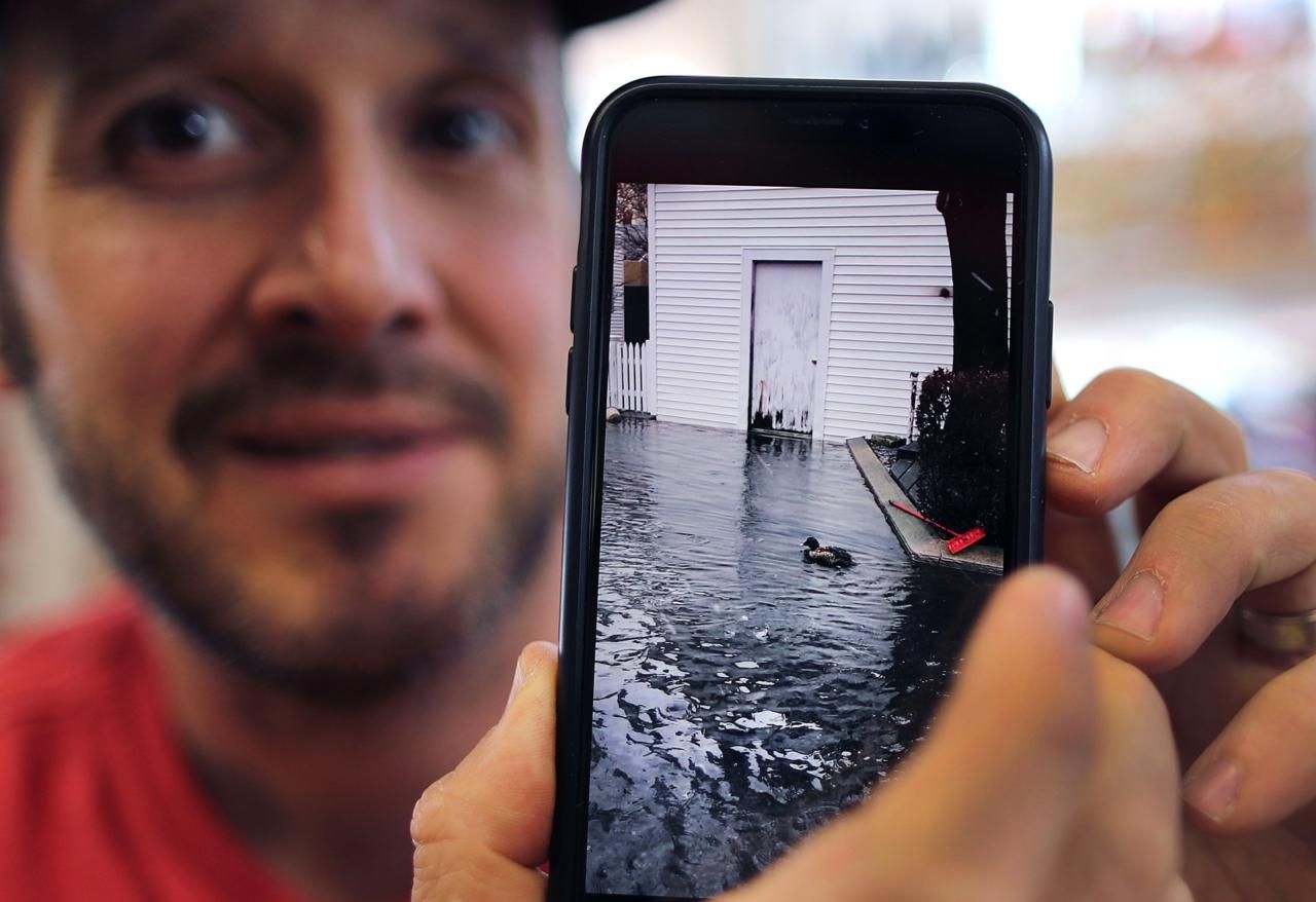 Vinnie Duarte, owner of Big Vin's liquor store on Commercial Street, showed a video of a duck swimming on flooded Gosnold Street during a January 2018 storm. Image by John Tlumacki. United States, 2019.