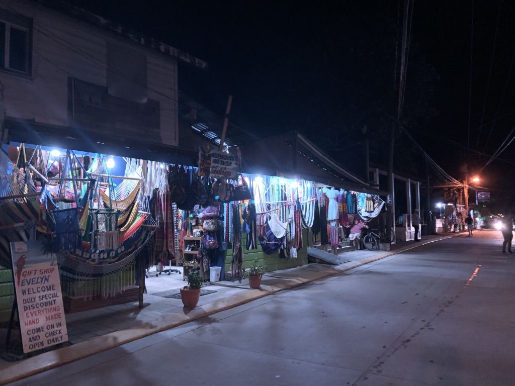 A row of souvenir shops illuminated at night in West End] Image by Jack Shangraw. Honduras, 2019.