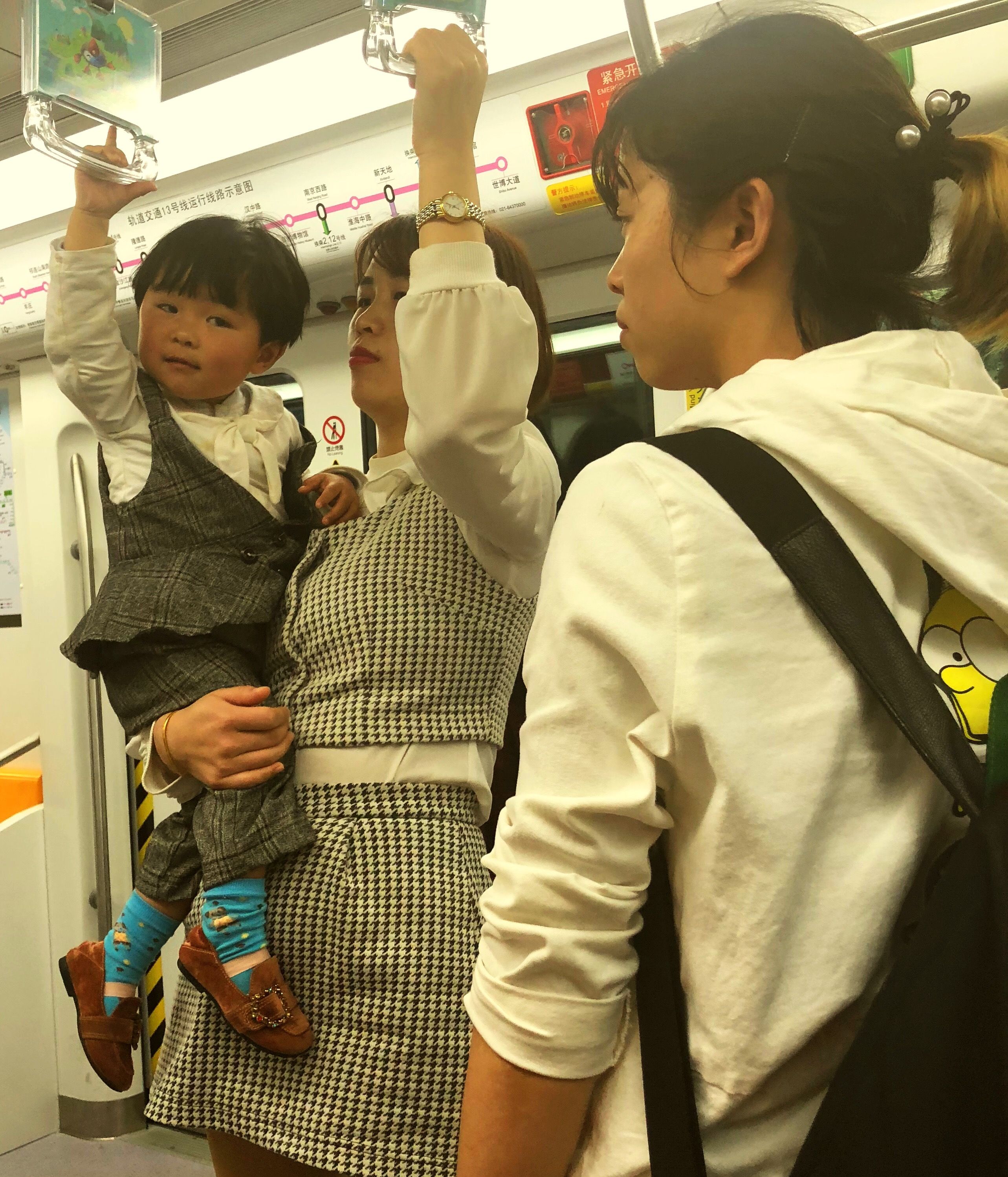 A young woman carrying her son on the train in Shanghai. Image by Argentina Maria-Vanderhorst. China, 2018.