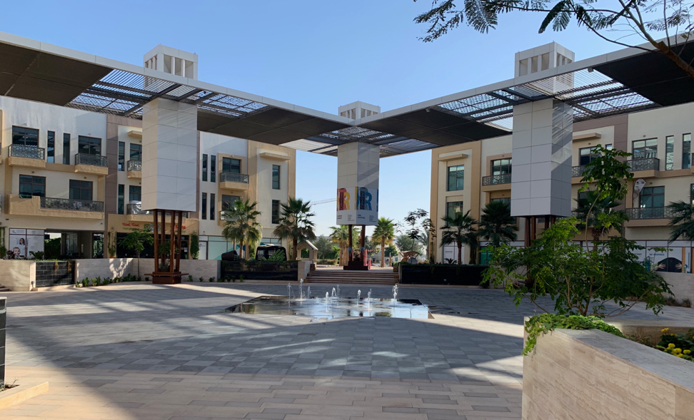 The main plaza of The Sustainable City is lined with apartments, shaded by a solar panel covering, and features a fountain which uses recycled grey water from the villas. Image by Anna Gleason. United Arab Emirates, 2019.