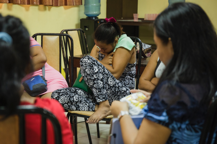 During a psychosocial session with Cruz, a woman who lost her father and sibling hugs herself. Her father and sibling were killed during a drug raid. According to the police, her relatives fought back, which is a common narrative that’s used to justify the killings. Image by Pat Nabong. Philippines, 2017.