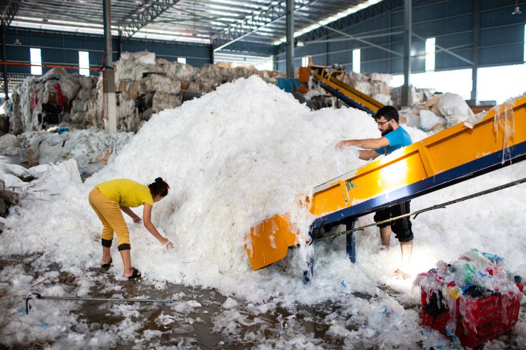 Shahid Ali (right) and a coworker at BioGreen Frontier, one of scores of recycling factories that popped up in Malaysia after China banned most plastic waste. Image by Sebastian Meyer. Malaysia, 2020.