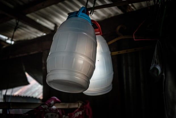 Jasmine Durana hopes that these containers, hanging from the rafters of her makeshift house in a Navotas slum, will help her launch a new business selling drinks in the market or in front of a local school. Image by James Whitlow Delano. Philippines, 2018. 