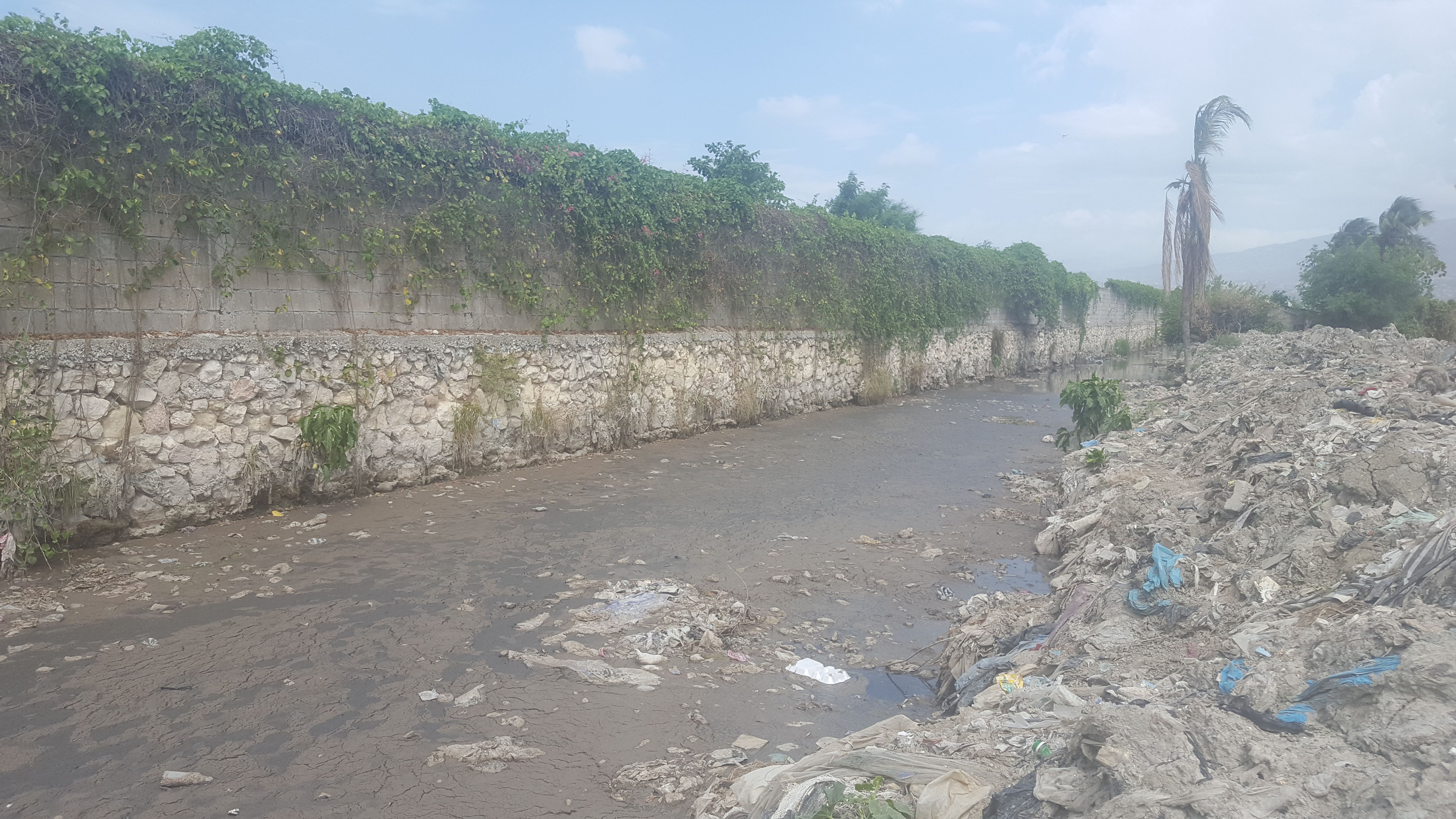 An open canal choked with raw sewage runs a few feet behind family homes in Cite Soleil. When it rains, the canals quickly overflow and flood the community with three feet or more of dangerous water and sludge. Image by Rebecca Hersher. Haiti, 2017.