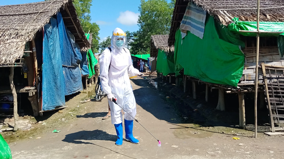 A volunteer sprays chemical disinfectant on shelters in Tain Nyo Internally Displaced Person Camp in Mrauk-U township, Rakhine State, Myanmar, as a COVID-19 prevention measure. Taken on September 2, 2020. Myanmar, 2020.