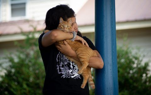 Tianna Sugars, 22, hugs her cat Tito on the front porch of her South Paris home. Sugars spoke about seeing the effects of her mother’s employment at home. Image by Linda Coan O’Kresik/BDN. United States.
