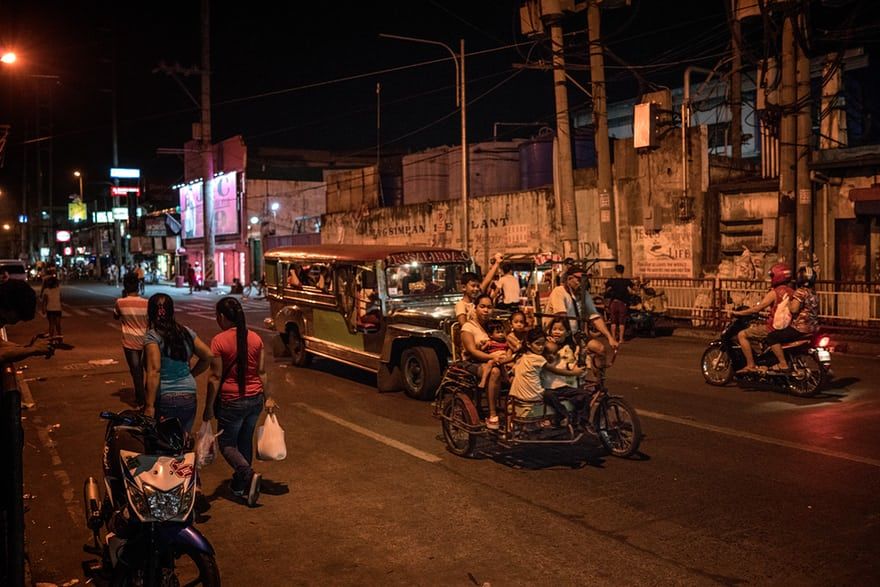 A pedi-trishaw filled to the brim with children on the main road outside of the Navotas slum, where Jasmine Durana lives. Image by James Whitlow Delano. Philippines, 2018.