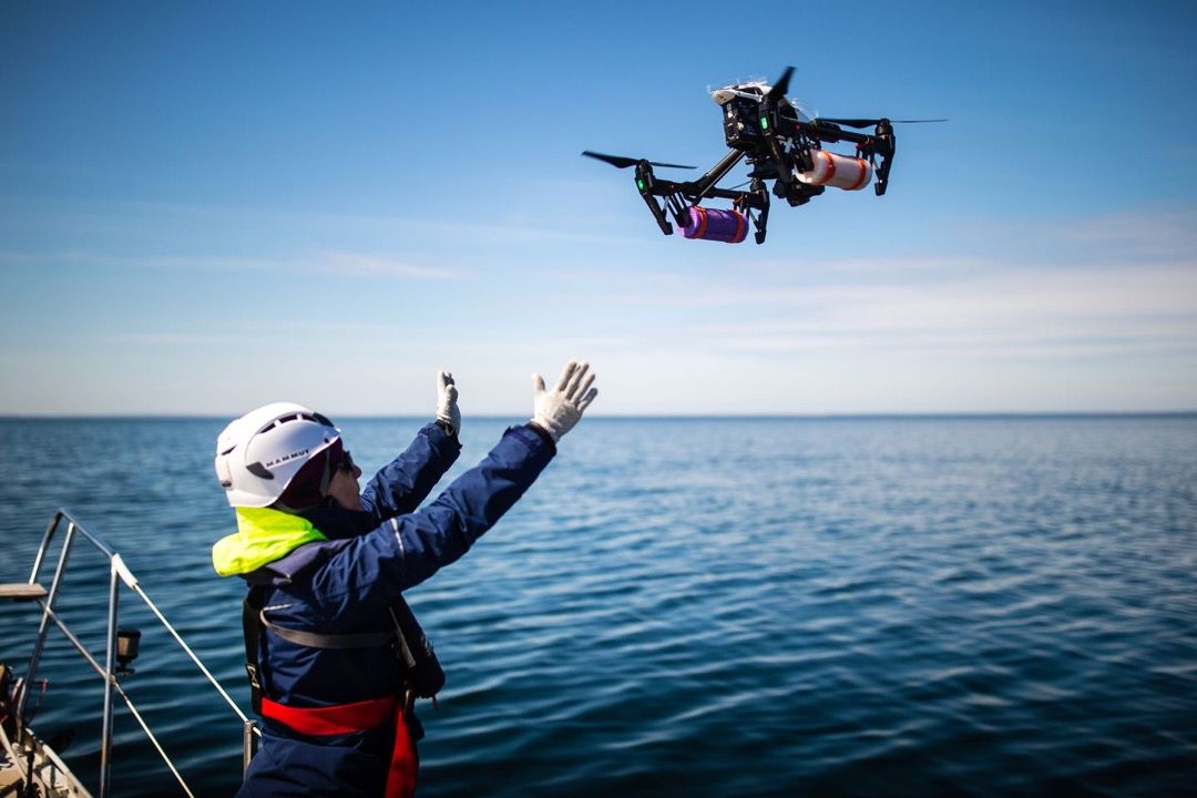 Carolyn Miller reached for a drone in Cape Cod Bay. Drones collect vapor samples that are tested to gauge the health of the whales. Image by Aram Boghosian/The Boston Globe. United Sates, 2019.
