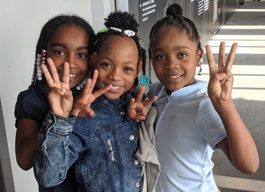 Students visiting the Peoria Riverfront Museum last fall hold up three fingers to show how many times they've visited the museum as part of the Every Student Initiative. Image by Peoria Riverfront Museum. United States, 2019.