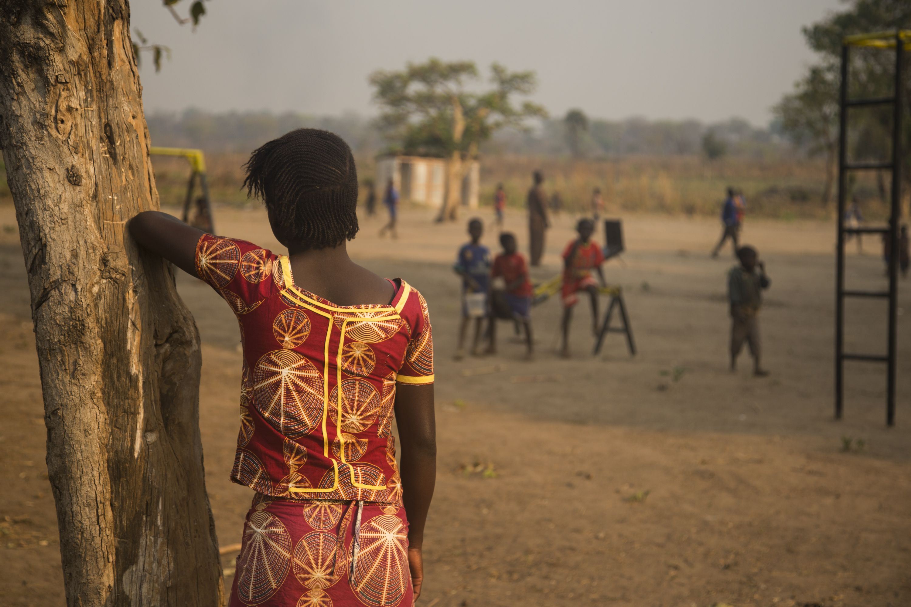 Rose, a teenage girl who was raped by militants, watches children play at a camp for displaced people. Image by Jack Losh. Central African Republic, 2018.