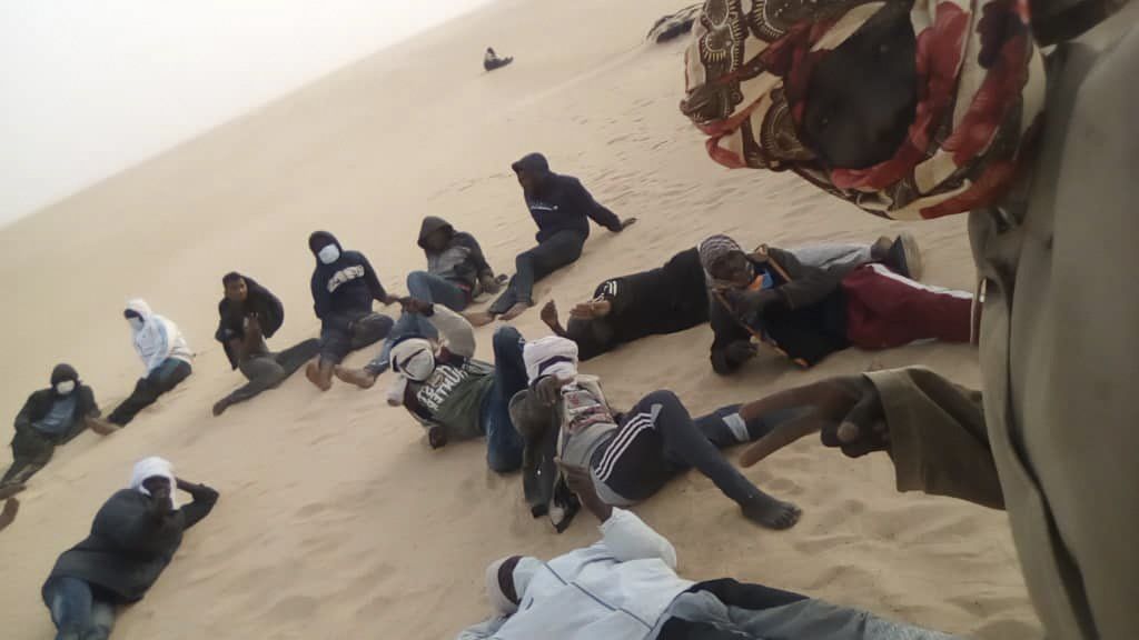 This March 22, 2020 provided by migrant Tayeb Saleh shows fellow migrants resting in the sand while they await help getting out in the Libyan Sahara near the border with Sudan. (Tayeb Saleh via AP)