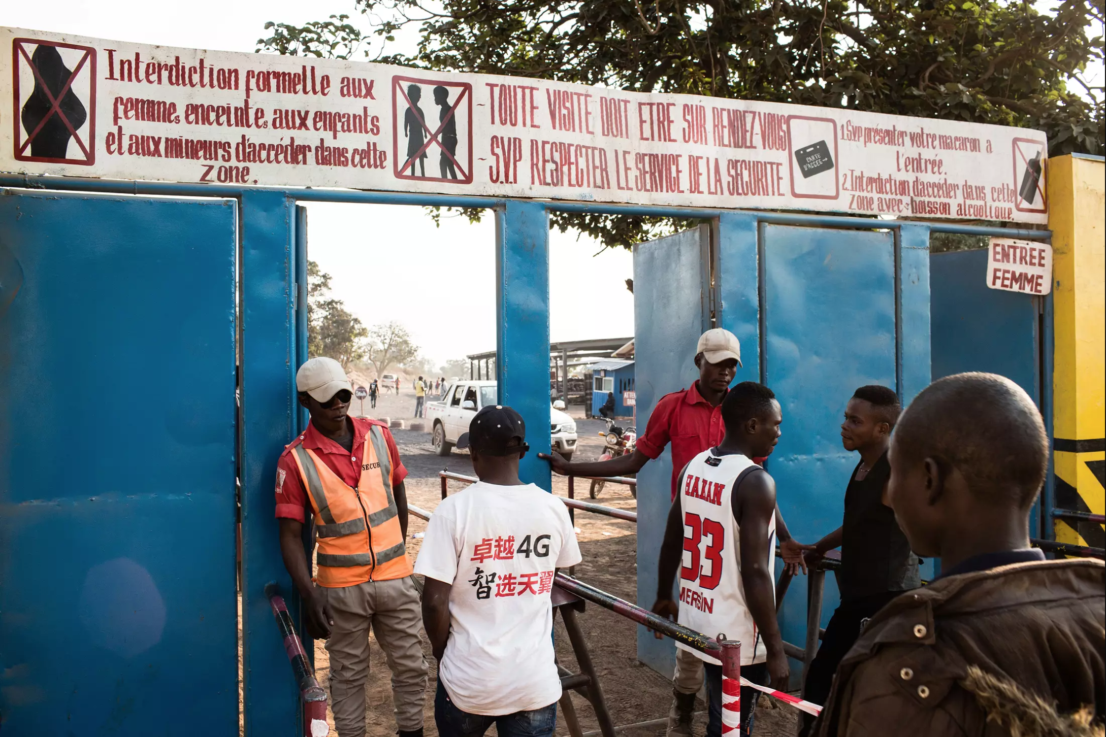 Signs in French at the entry gate to the Kasulo mine say pregnant women and children under 18 are not allowed inside. Image by Sebastian Meyer. Democratic Republic of Congo, 2018.