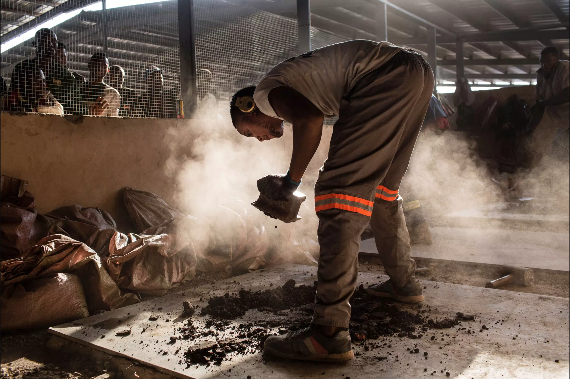 A miner crushes cobalt that will be tested for purity at the Kasulo mine depot. Image by Sebastian Meyer. Democratic Republic of Congo, 2018.