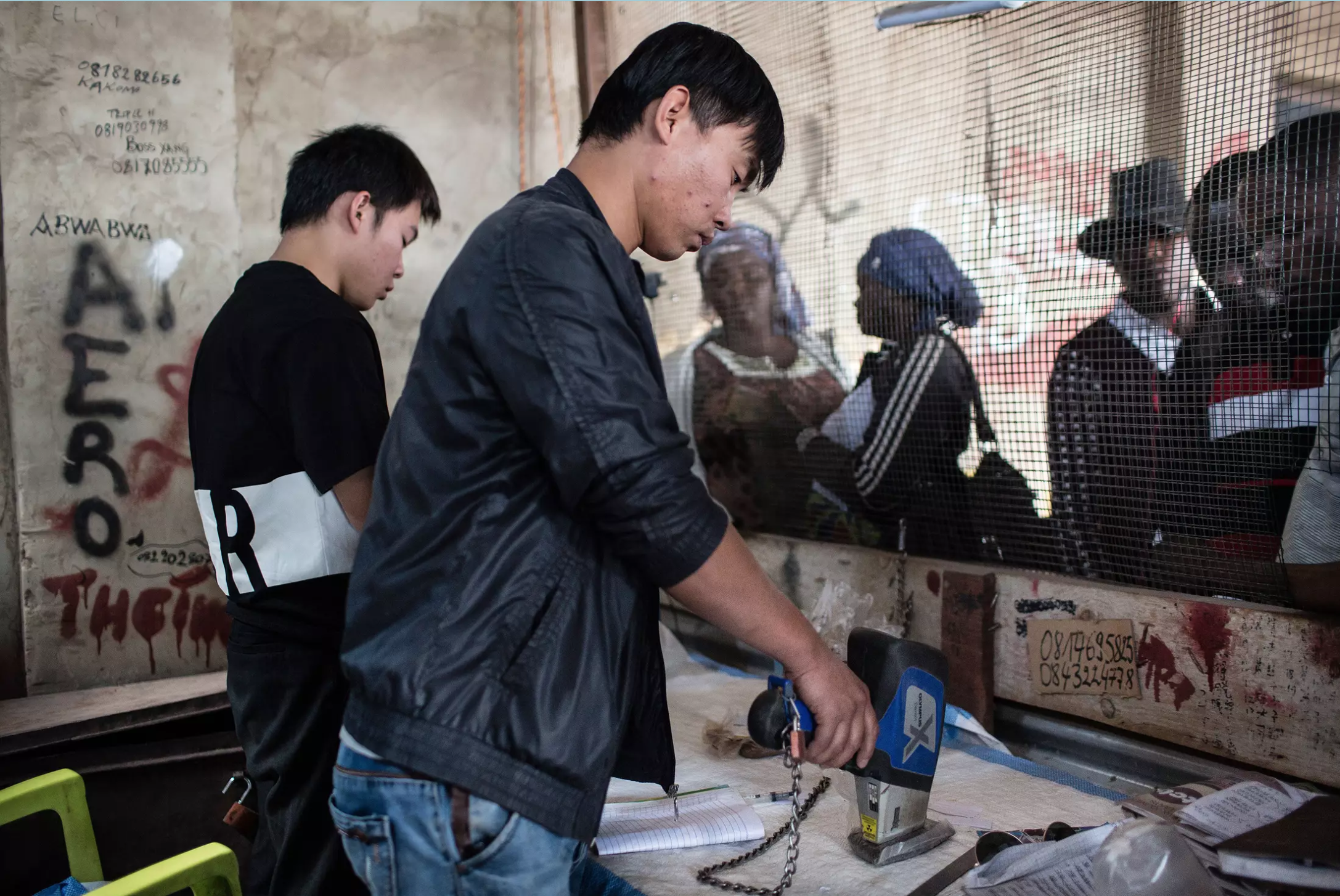 Cobalt buyer Xu Bin Liu, 30, from Hebei province in China, tests the purity of cobalt he’s buying at the Musompo market on the outskirts of Kolwezi. Image by Sebastian Meyer. Democratic Republic of Congo, 2018.
