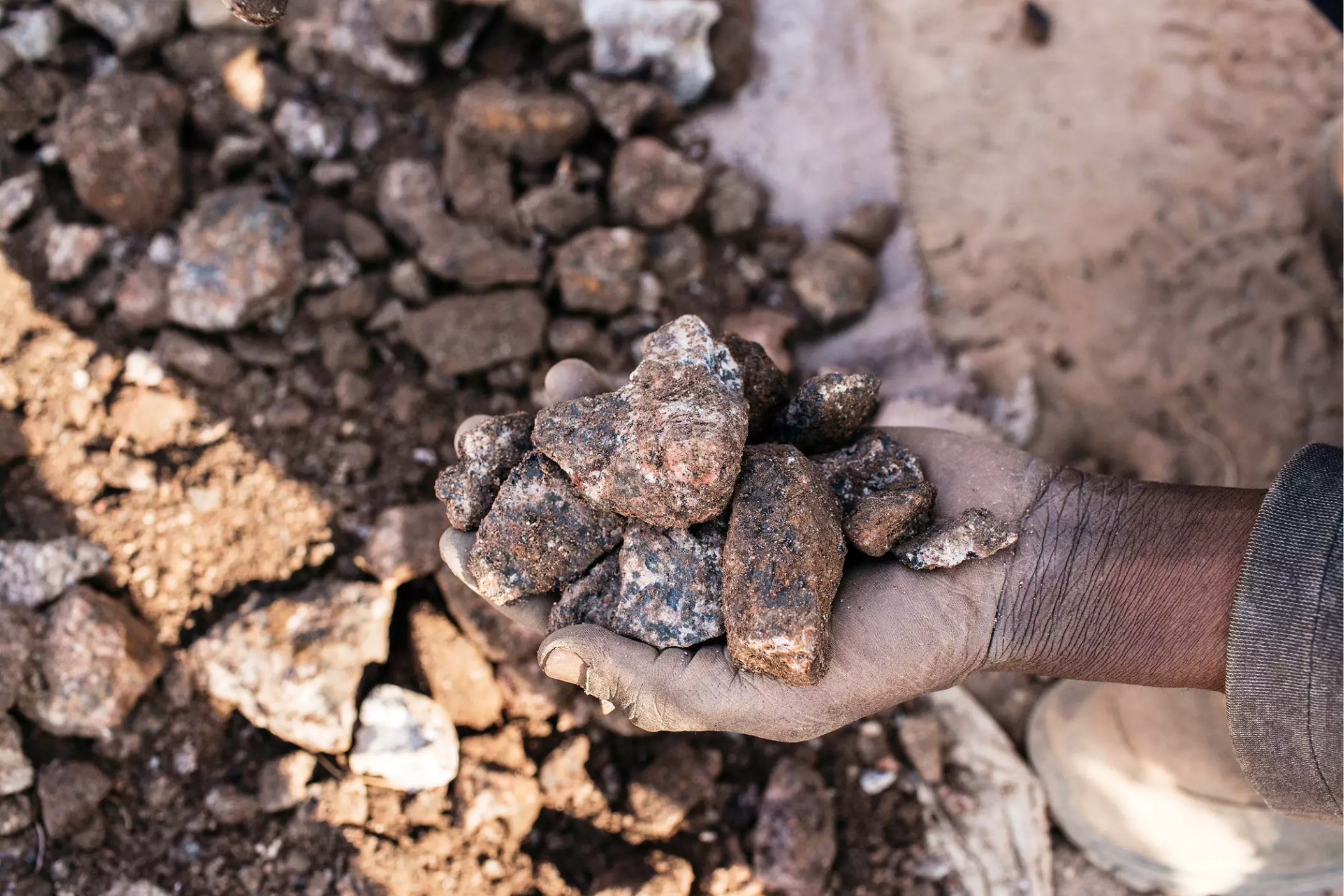 A miner holds chunks of cobalt he has dug out at the Kasulo mine near Kolwezi in the DRC. Image by Sebastian Meyer. Democratic Republic of Congo, 2018.