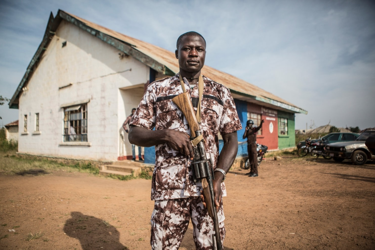 Bitrus Goting, 29, who joined the volunteer peacekeepers in Barkin Ladi in 2012, carries a homemade rifle outside the group’s headquarters. Image by Jane Hahn. Nigeria, 2018.