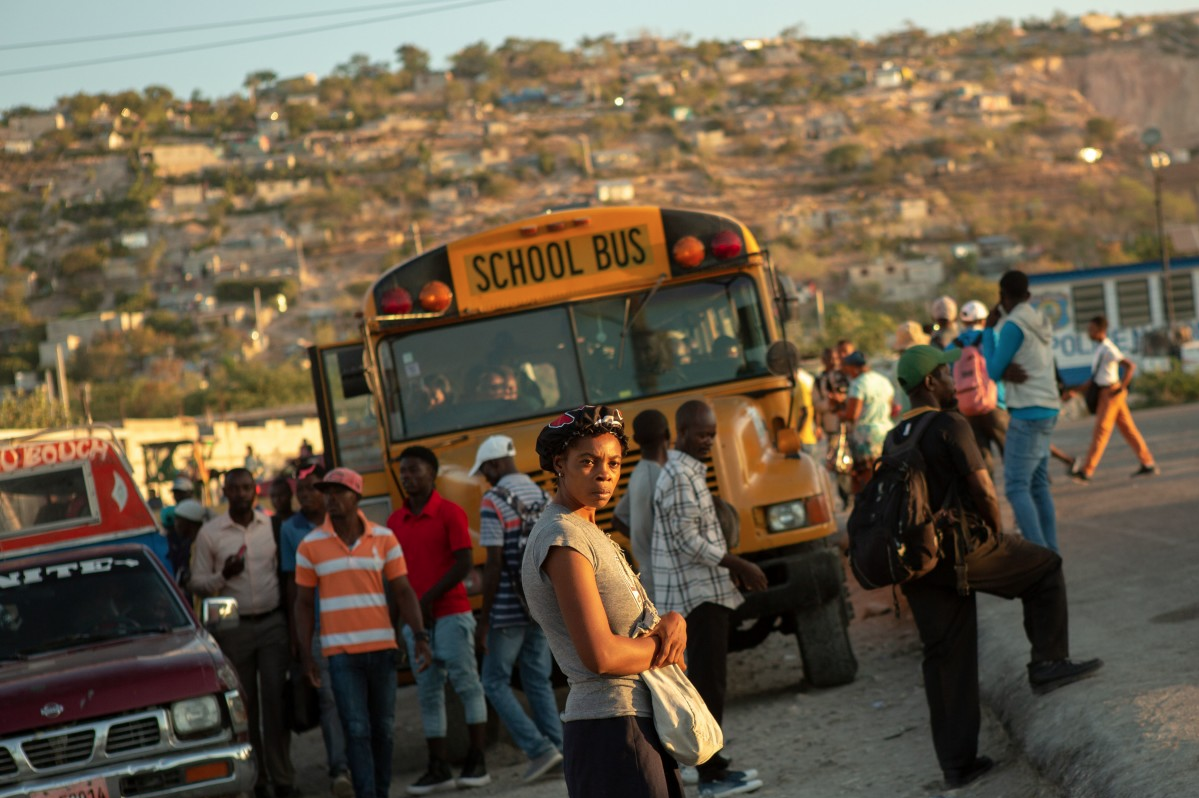 Commuters stream onto busses for an early morning commute to Port-au-Prince, the nation’s capital. An estimated 30 percent of Canaan's residents commute out of the area each day to get to work or school. Image by Allison Shelley. Haiti, 2019.