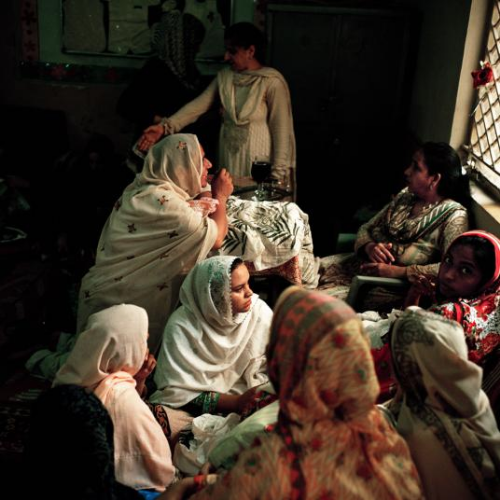 Women show their hand-embroidered textiles to Tasleem Akhtar, 55, who runs a vocational center in a village near Islamabad. A women’s empowerment organization called Behbud has trained about 300 women who are working here. The women use their earnings to send their children to school. Image by Sara Hylton/National Geographic. Pakistan, 2019.
