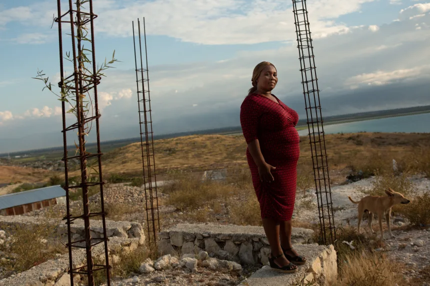 Carmen Cean, a.k.a. "Madame Roy," poses for a photo on a foundation near her home on a hilltop in the Village de Pecheur neighborhood of greater Canaan. Image by Allison Shelley. Haiti, 2019.