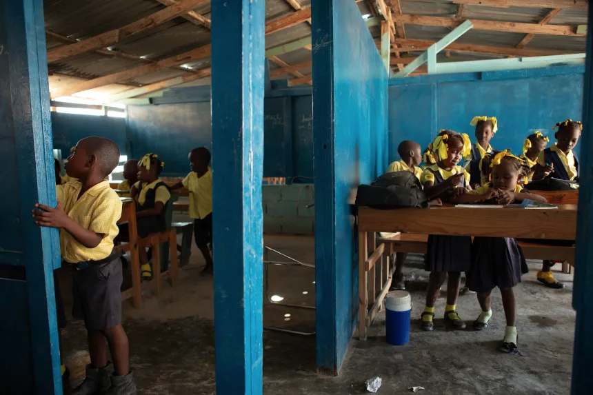 Students of various grades participate in classroom lessons in classrooms separated by partial walls at Institution Mixte Cean Carmen, a K-12 school in the Village de Pecheur neighborhood of greater Canaan. Image by Allison Shelley. Haiti, 2019.