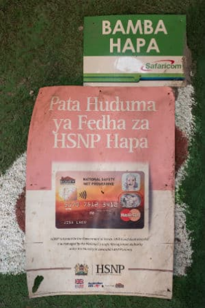 Ads for HSNP posted on the wall of a shop in Wajir. Image by Peter DiCampo. Kenya, 2018.