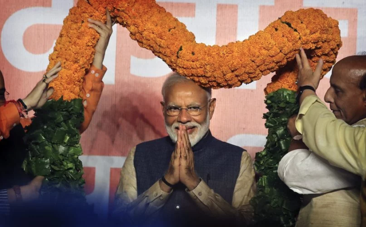 Indian Prime Minister Narendra Modi receives a giant floral garland from party leaders at their headquarters in New Delhi, India, on May 23, 2019, after winning the elections. Image by Manish Swarup / AP. India, 2019.