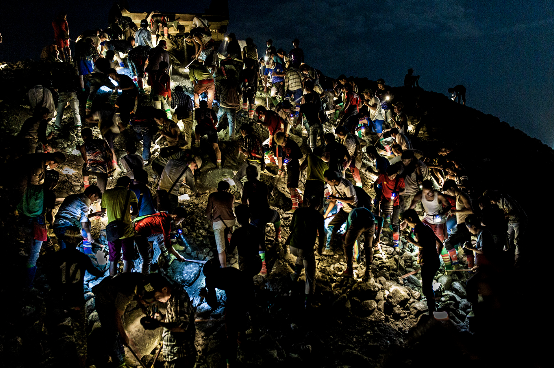 Freelance miners search for jade stones at night with torchlights on a waste site in Hpakant on May 18, 2019. Image by Hkun Lat. Myanmar, 2019. 