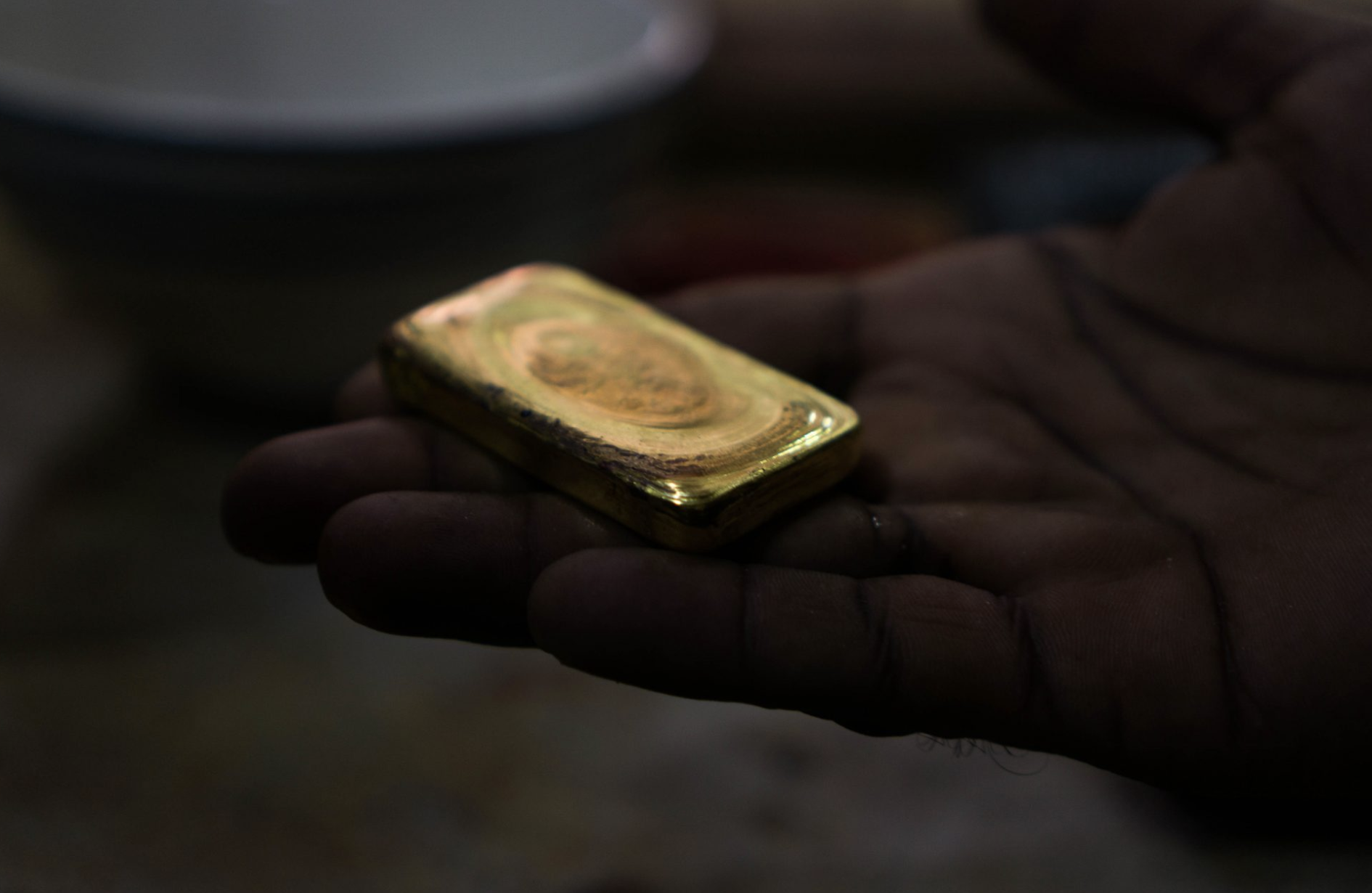 A miner shows the gold bar shaped after he 'burns' the raw gold to remove residual mercury and further refine the precious metal. Image by Bram Ebus. Guyana, undated.