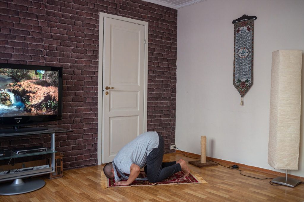 Wael prays in his living room in Bergen, Norway. Image by Bradley Secker. Norway, 2020.