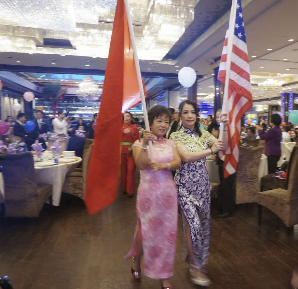 Former Tingjiang Secondary School students hold Chinese and American flags at an alumni association meeting in September. The association boasts more than 15,000 members in the United States. Image by Rong Xiaoqing. United States, 2016.

