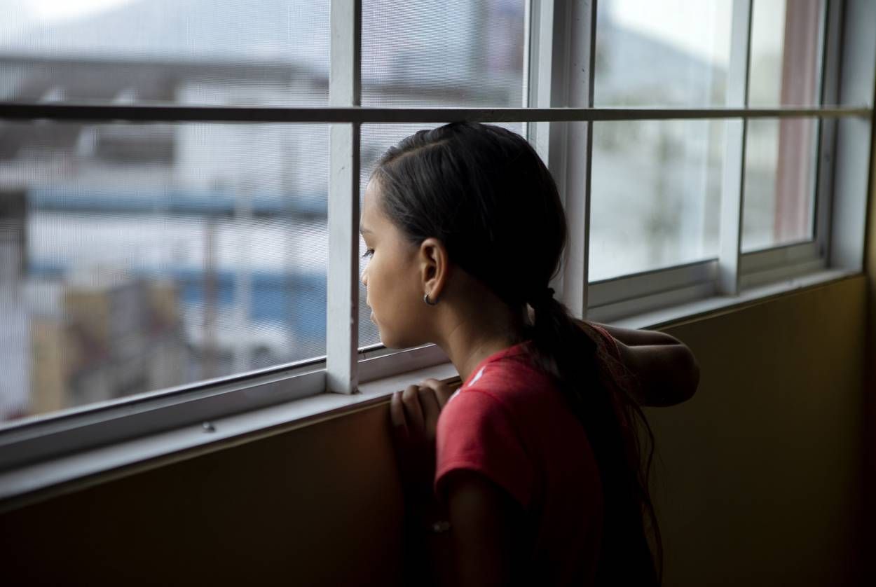Elibette Trujillo looks out of a window at Casa Indi in Monterrey, Nuevo Leon on Aug. 6, 2019. Elibette migrated from Honduras with her mother Nora Valdez. The pair are waiting at the shelter until their asylum hearing. Image by Miguel Gutierrez Jr. Mexico, 2019.