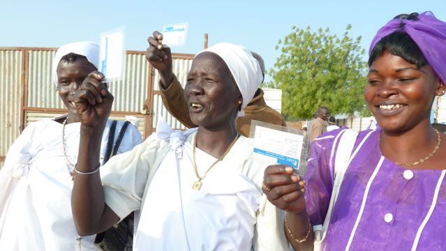 Congregants at St Martin de Porres church in Bentiu, South Sudan display their voter ID cards on their way to the polling center. Image by Fred de Sam Lazaro. Sudan, 2011.