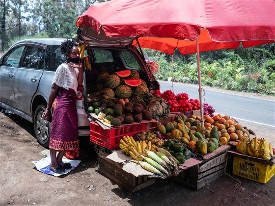 A woman sells vegetables out the back of a vehicle Oct. 16 in a suburb of Nairobi, Kenya. Some Uber drivers have adapted their vehicles for alternative uses, saying they earn more selling fruit and vegetables than driving with the app. Image by Nichole Sobecki/NBC News. Kenya, 2020.
