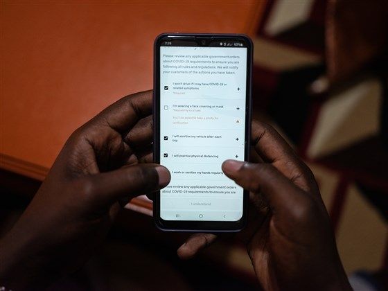 Uber driver Emmanuel Bitok, one of more than 80 drivers who spoke with NBC News, confirms the safety requirements on the Uber app before heading out for the day. Image by Nichole Sobecki/NBC News. Kenya, 2020.
