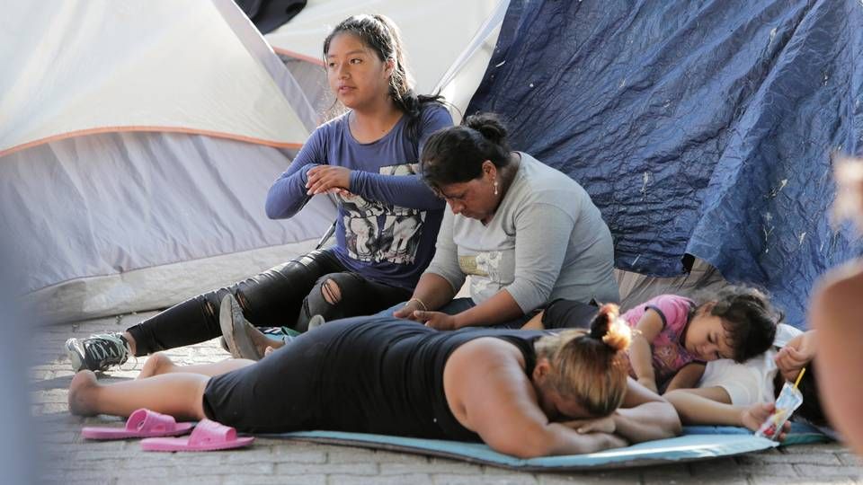 A migrant family waits in the shade on the Matamoros side of the Gateway International Bridge. Many migrants who cannot afford to rent rooms stay in this makeshift camp while waiting to ask for asylum in the United States. Image by Jose A. Iglesias. Mexico, 2019.